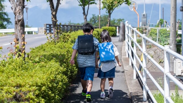 歩道を歩くランドセルを背負った兄弟