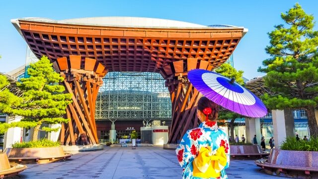 日傘をさして街に立つ着物女性